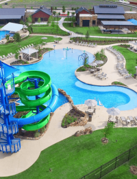 Waterpark aerial view featuring slides, large pool, and green area in Forney, TX