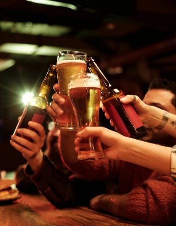 Raising beer glasses together in a bar