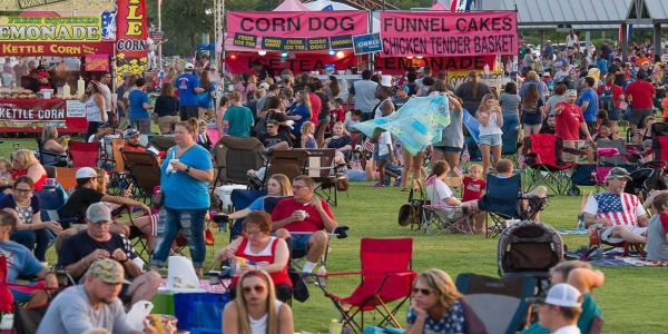 Crowded local fair with people visiting food vendors on an outside lawn