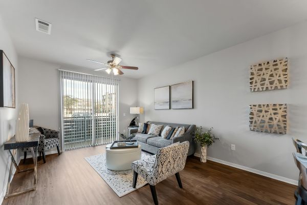 Gateway Cedars apartment living room with large windows and ceiling fan and furnished with sofa, chairs, and tables